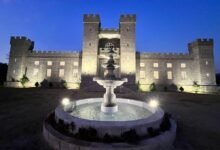 Fachada iluminada do Castelo da Torre na Paraíba com fonte central ao anoitecer